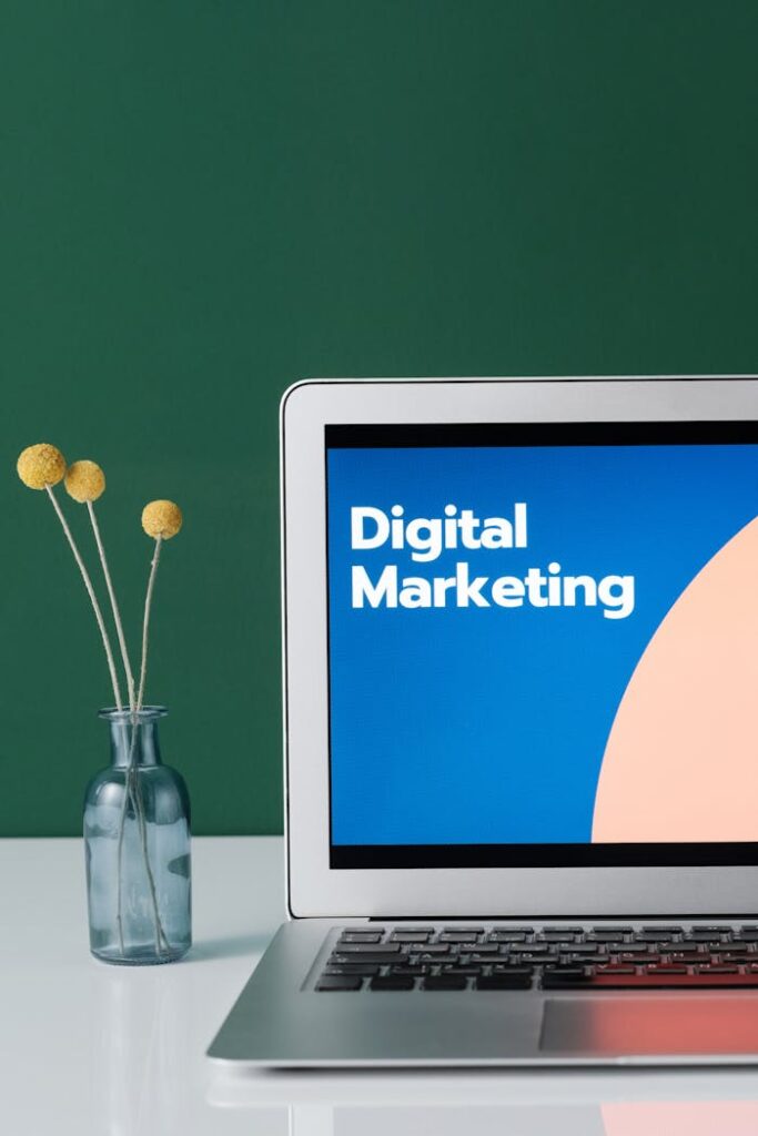 pexels photo 6483583 A laptop displaying 'Digital Marketing' with a minimalist floral decor in a glass vase.